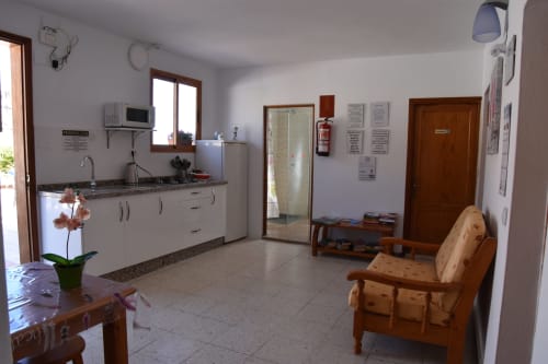 Área común del hostal Pension Eva en Puerto de Mogán con cocina, mesa de comedor, silla de madera y espejo
