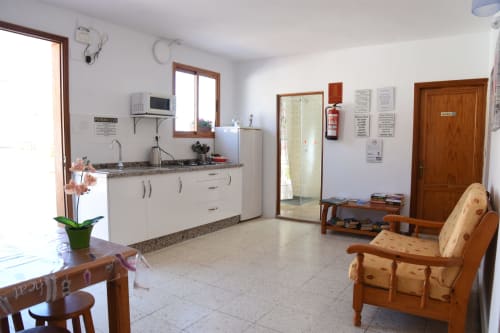 Zona común del hostal Pension Eva en Puerto de Mogán con cocina, muebles de madera y azulejos de barro