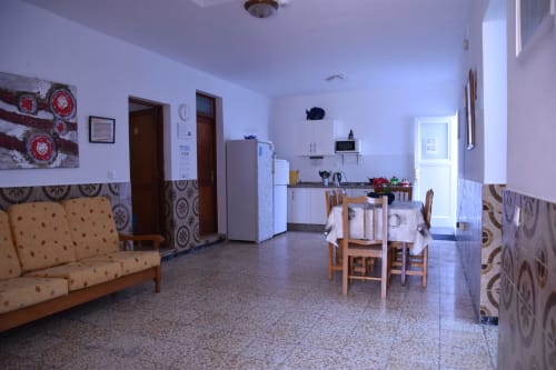 Área común de la Pensión Eva en Puerto de Mogán con cocina, mesa de comedor, sofá y piso de baldosas de terracota