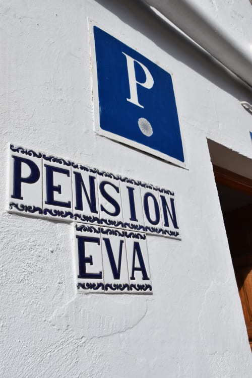 Letrero del hostal Pension Eva con símbolo de aparcamiento en Puerto de Mogán, España