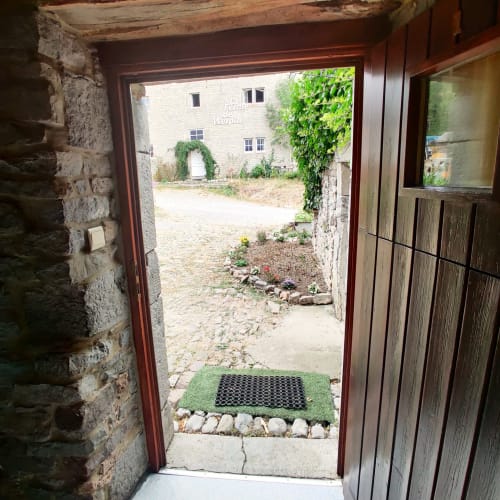 Ingang van het studio-appartement in La Ferme De Werpin met directe toegang tot tuin, stenen muren en groene deurmat