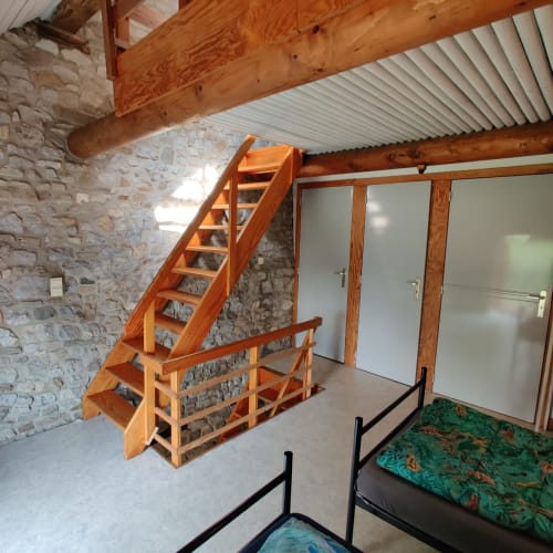 Wooden staircase and beds in rustic stone apartment at La Ferme De Werpin, Hotton