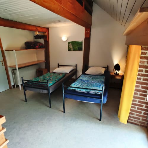 Cozy dormitory-style bedroom at La Ferme De Werpin with two single beds, shelving, and brick accent wall