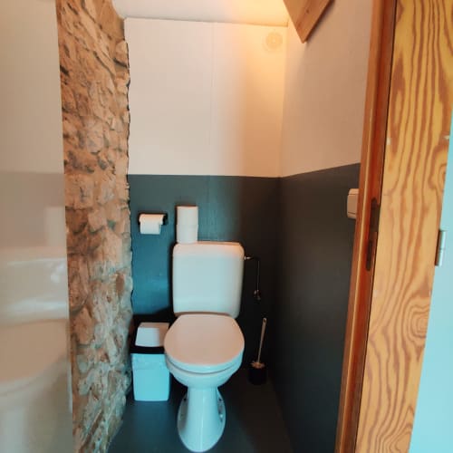 Compact toilet room with turquoise lower walls, white upper walls, toilet, sink and paper holder at La Ferme De Werpin