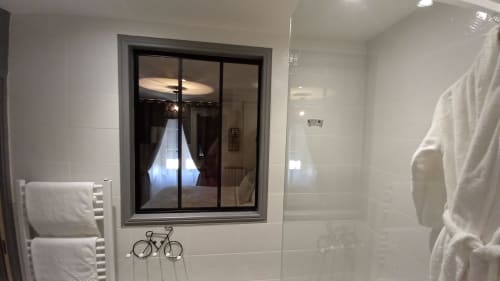 Salle de bains moderne à La Maison De Fleurat avec douche à cadre noir, carrelage blanc, porte-serviettes et décoration vélo