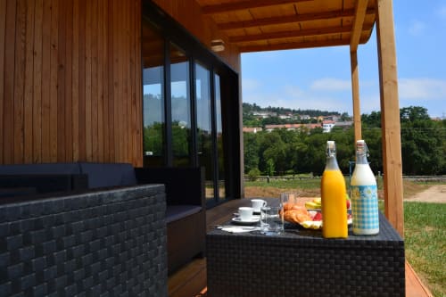 Terraza Cabaña Sarela con vistas al jardín, pérgola de madera, asientos negros y bebidas en Cabañas Compostela Santiago