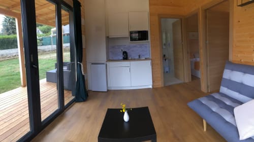 Interior moderno de cabaña en Cabañas Compostela con cocina, sofá a rayas, pisos de madera y acceso a terraza con vista al jardín
