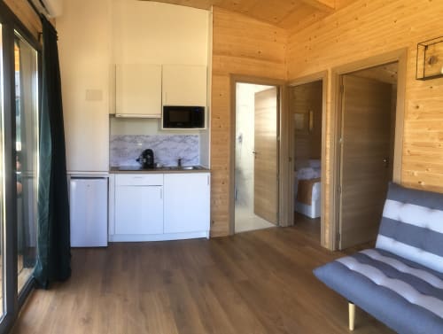Estudio Cabaña Sarela con kitchenette, interior de madera, camas y puertas con vistas al jardín en Cabañas Compostela, Santiago de