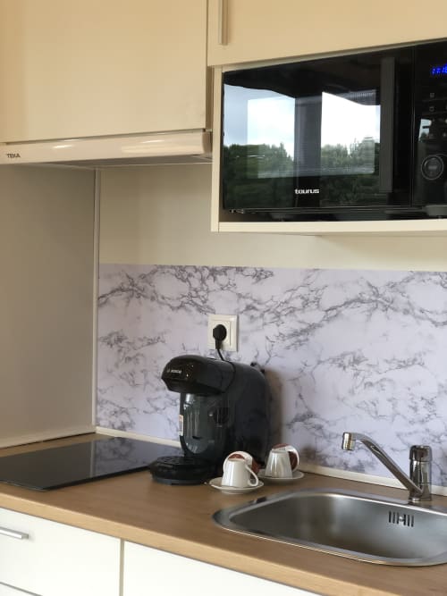 Cocina moderna en Cabañas Compostela con backsplash de mármol, microondas, cafetera y ventana con vista al jardín en Santiago de