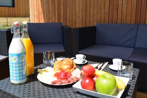 Desayuno al aire libre en Cabañas Compostela con frutas frescas, pastelería, bebidas y servicios de mesa en la terraza