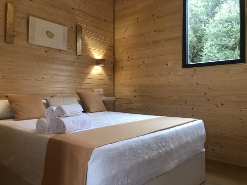 Habitación de cabaña de madera en Cabañas Compostela con cama queen, toallas blancas, vista al jardín y comodidades modernas en Santiago