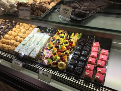 Vetrina di pasticceria ad Alloggio Le Casette Verona con dolci italiani, sfogliatelle colorate, piccoli pasticcini rosa e