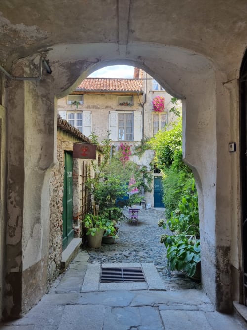Affascinante arcata in pietra che conduce a una corte fiorita della B&B La Corte a Ovada, Italia