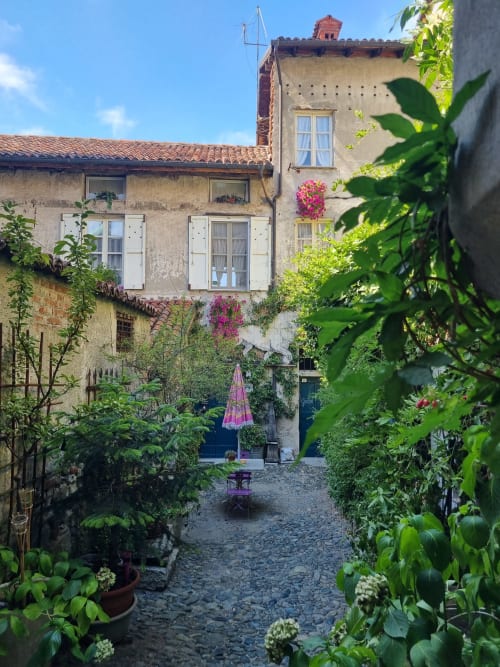 Affascinante corte interna della B&B La Corte Ovada a Ovada, Italia, con lussureggiante vegetazione, piante fiorite e pietra rustica
