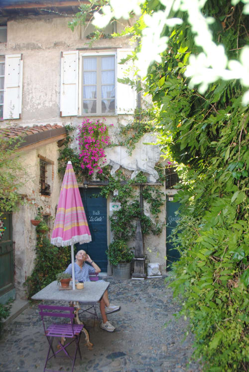 Ospite rilassato nel suggestivo cortile di B&B La Corte a Ovada, circondato da edera rigogliosa e vivaci fiori fucsia.