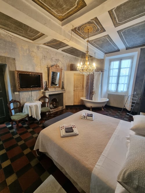 Lussuosa camera da letto presso B&B La Corte Ovada a Ovada con vasca freestanding, lampadario e vista sul giardino