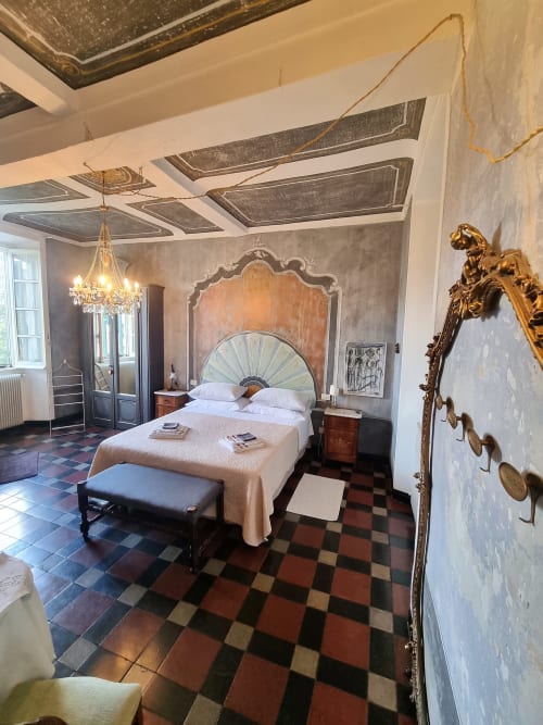 Elegante camera da letto della B&B La Corte Ovada a Ovada con testata ornata, lampadari e pavimento in piastrelle a scacchi