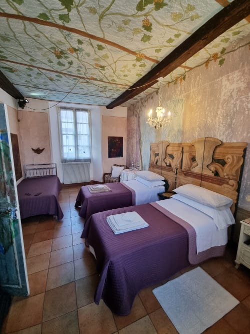 Spazioso guest room al B&B La Corte Ovada con letti gemelli, testiere in legno, soffitto decorato a motivo di vite e giardino