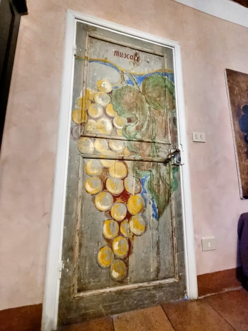 Affresco nella B&B La Corte Ovada di Ovada con uva dipinta e cherubino su antica porta in legno