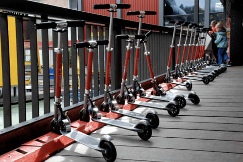 Row of red and black scooters lined up on a deck at Alloggio Le Casette in Verona, with a child in blue nearby
