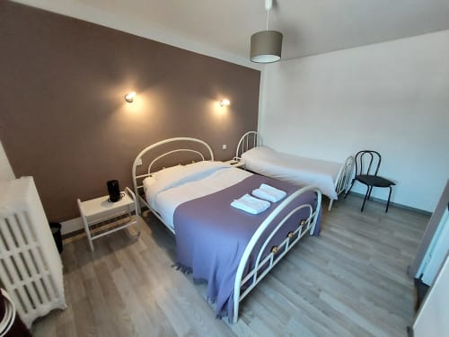 Chambre taupe au Comtois B&B à Saône avec lits jumeaux en métal, literie blanche, appliques murales et décoration moderne