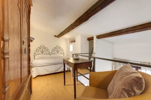 Sleep Tight Florence loft bedroom with exposed beams, ornate headboard, and mezzanine seating area in Firenze