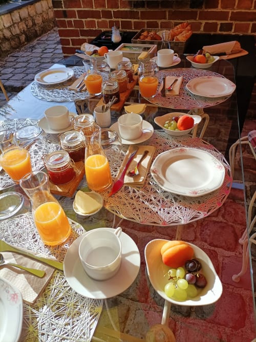 Outdoor breakfast spread at Au Repos De La Licorne B&B in Gommegnies with fresh juice, pastries, fruit 