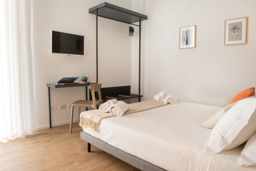 Camera moderna a Sicilianinsta Rooms di Catania con letto, area di lavoro, TV e arredamento minimalista