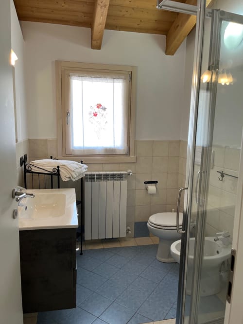 Bagno luminoso nel monolocale di Vezza d'Oglio con lavandino, wc, radiatore e box doccia