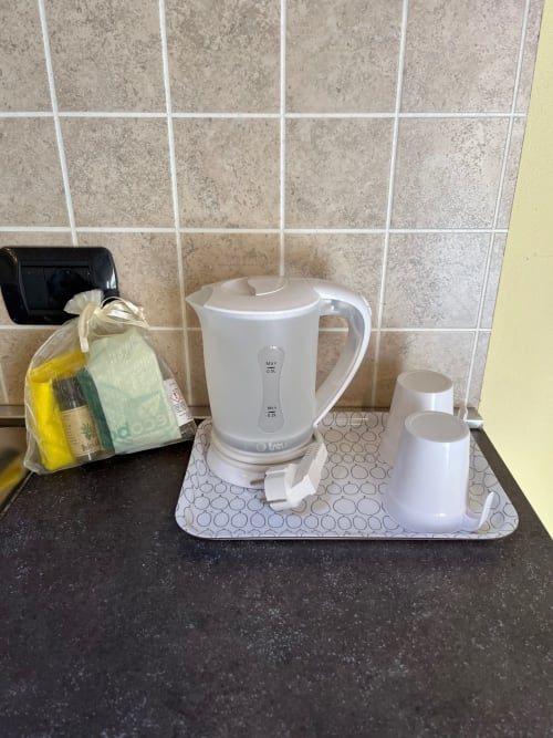Piccola cucina in monolocale di Residence La Corte con bollitore elettrico bianco e tazze sul bancone