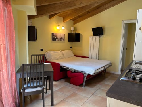 Studio in Residence La Corte a Vezza d'Oglio con divano letto rosso, travi a vista, pareti gialle, TV a schermo piatto e
