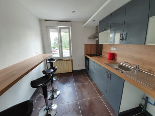 Cuisine moderne avec plan de travail en bois, meubles gris et bar de la chambre B NancyRoom à Vandoeuvre-les-Nancy
