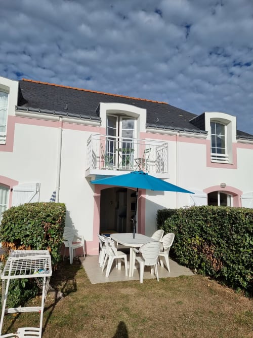 Terrasse d'appartement face mer à Loc'Maria, Belle Île en Mer, avec parasol bleu et mobilier blanc donnant sur