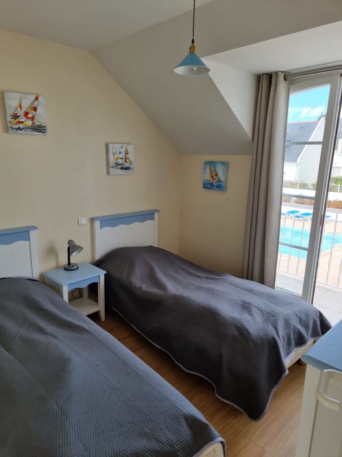Chambre côtière lumineuse avec deux lits, suspension bleue, décor nautique et accès balcon vue mer à Loc'Maria,