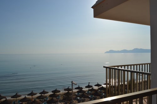 Hotel Sa Roqueta beachfront view from balcony overlooking Can Picafort bay with parasols and calm waters