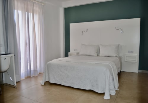 Modern bedroom at Hotel Sa Roqueta in Can Picafort with white bed, green accent wall, and balcony access