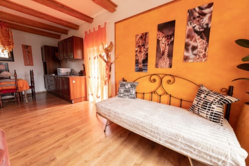 Camera luminosa con pareti arancioni brillanti presso Il Podere Prato a Predappio Alta, letto in ferro battuto, artwork giraffa e travi in legno