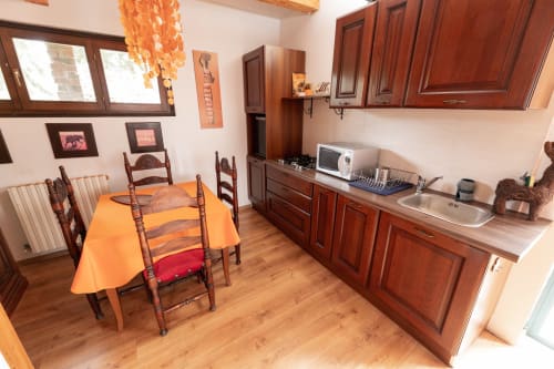 Accogliente zona cucina-pranzo a Il Podere Prato con mobili in legno, tovaglia arancione e fascino tradizionale italiano a Predappio