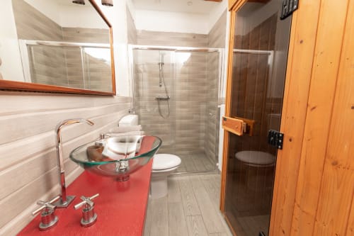 Bagno moderno nell'appartamento Il Podere Prato a Predappio Alta con vanity rosso, doccia in vetro e dettagli in legno
