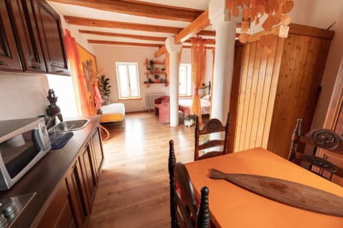 Appartamento open-plan a Il Podere Prato con tavolo da pranzo, cucina e camera da letto visibili attraverso travi in legno