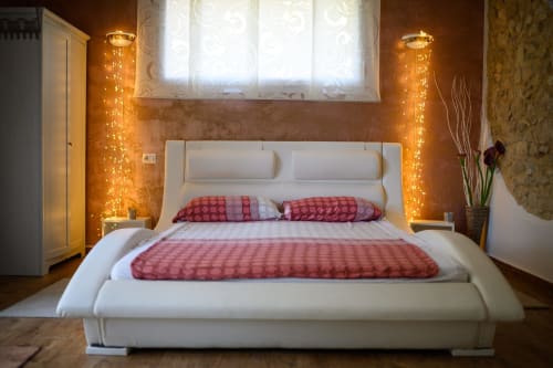 Letto bianco moderno con cuscini rossi presso l'appartamento Il Podere Prato a Predappio Alta, illuminazione ambrata calda e muri con texture