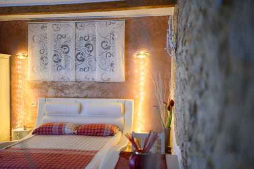 Camera accogliente a Il Podere Prato con luci calde, letto bianco, cuscini decorati e muri in pietra rustica