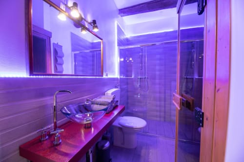 Bagno moderno di Il Podere Prato con illuminazione neon viola, vanità rossa, box doccia in vetro e specchio illuminato