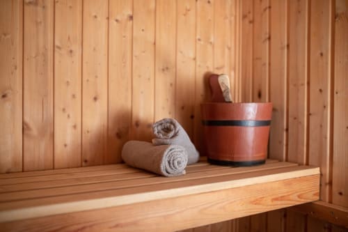 Interno di sauna in legno con asciugamani arrotolati e secchio di legno presso Il Podere Prato, Predappio Alta