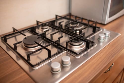 Piano cottura a gas in acciaio inossidabile con quattro fuochi nella cucina moderna dell'hotel Il Podere Prato a Predappio Alta, Italia