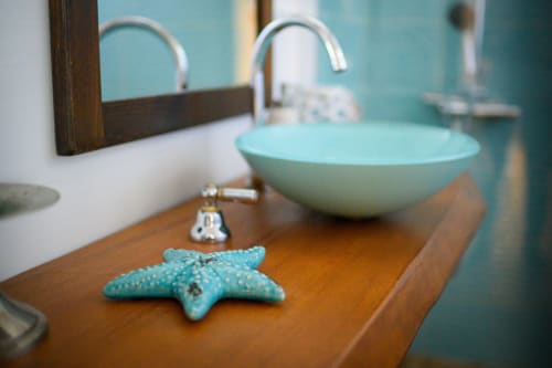 Bagno costiero a Il Podere Prato con lavabo turchese, rubinetto cromato, decorazione di stelle marine su mobiletto in legno e specchio