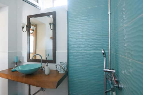 Bagno moderno presso Il Podere Prato con pareti piastrellate ondulate color turchese, mobile bagno in legno e lavabo a vessel