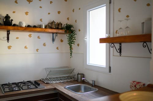 Angolo cucina di Il Podere Prato con cucina a gas, lavello, ripiani in legno, decorazioni autunnali e luce mattutina dalla finestra