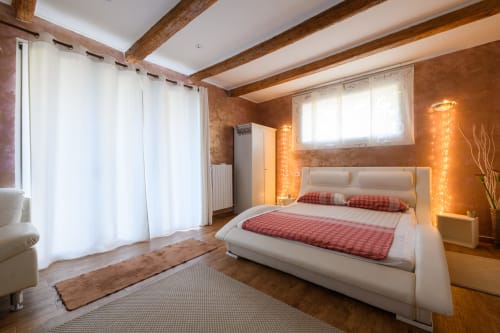 Spaziosa camera da letto a Il Podere Prato con letto matrimoniale, travi in legno, pareti color arancio e illuminazione calda a Predappio