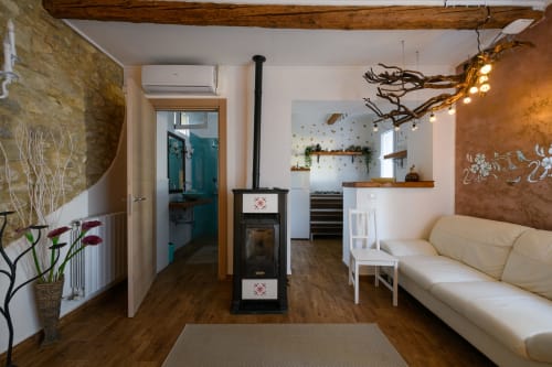 Soggiorno rustico a Il Podere Prato con travi in legno, divano color crema, stufa nera e illuminazione calda a Predappio Alta